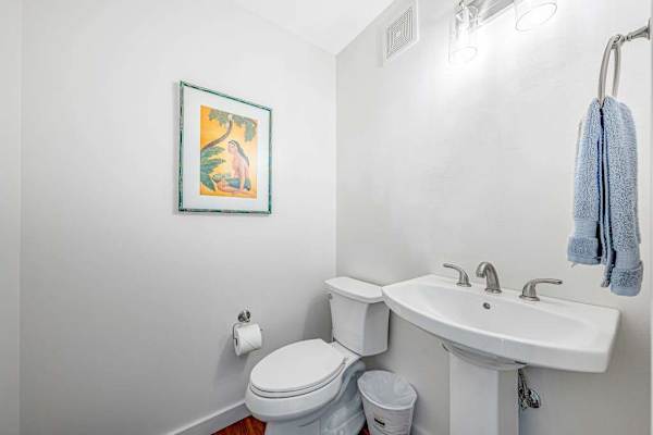 Clean half bath with pedestal sink & toilet located near garage/laundry