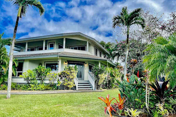 Beautiful daytime view of the property surrounded by vibrant gardens and mature trees