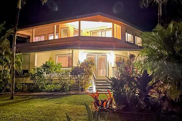 Evening view of home exterior & illuminated tropical landscaping