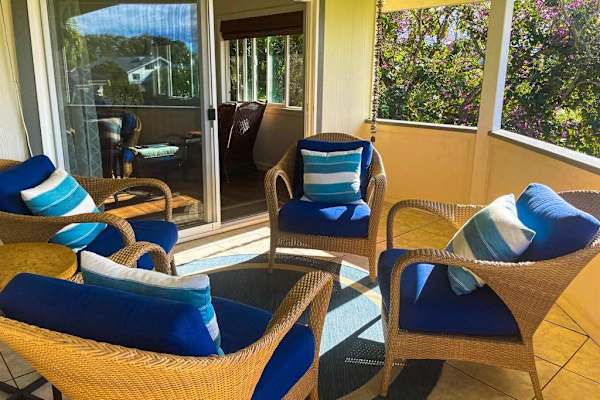 Covered porch featuring wicker armchairs & blue cushions