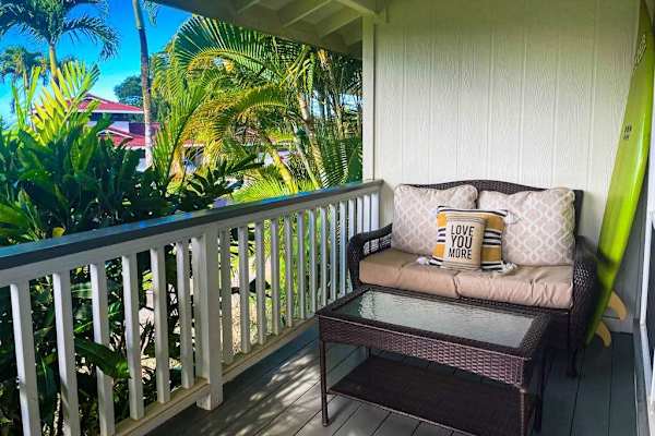 Covered private balcony with cozy outdoor loveseat and tropical views