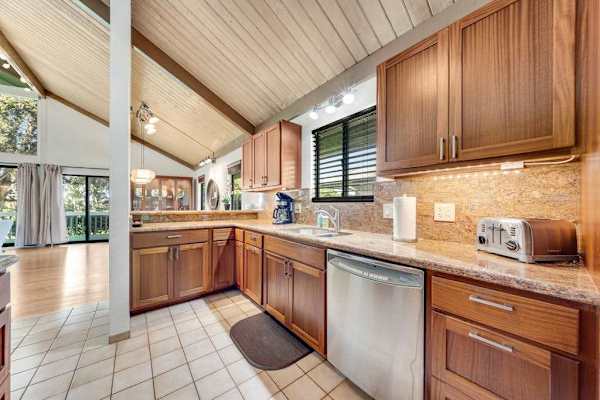 Vaulted kitchen gleams with wooden cabinets dishwasher and generous counters