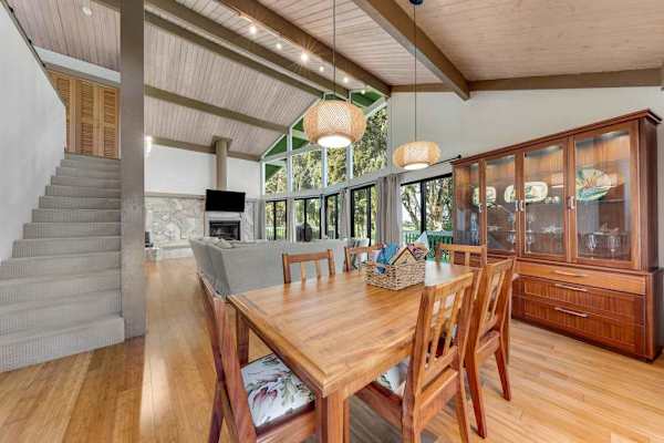 Wooden dining table anchors bright meals beside airy island kitchen