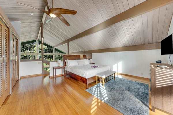 Warm timber floors frame restful bed beside breezy sliding doors