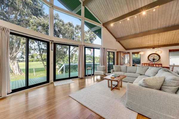 Sun drenched lounge opens toward lawns through dramatic glass walls