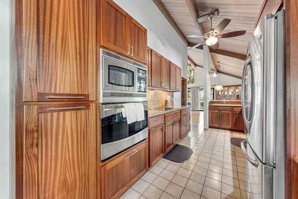 Stainless appliances complement timber cabinets beneath vaulted ceiling and skylight