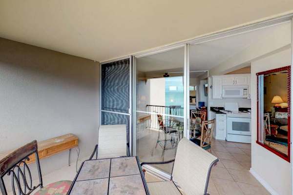 Featuring a glass-topped dining table and metal-framed chairs overlooking the ocean.