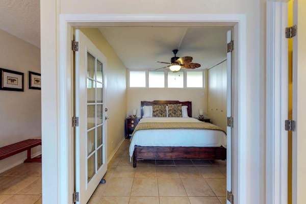 Bedroom, featuring a king bed, French doors, and a palm leaf fan.