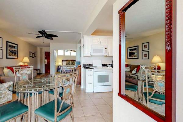Dining area featuring a red-framed mirror and teal dining chairs
