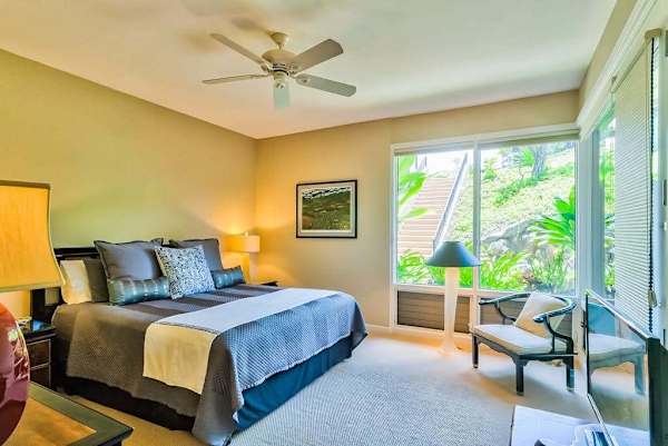Master bedroom with king bed and large windows for tropical views and private lanai access.