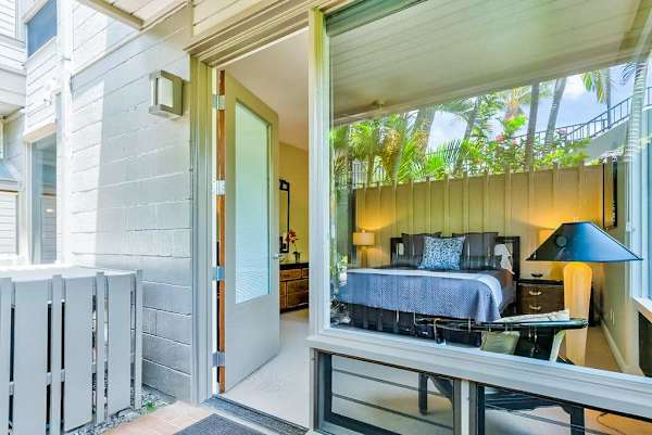 Master bedroom with king bed and large windows for tropical views and private lanai access.