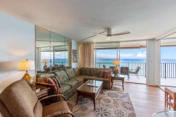 Living room with sofa bed, flat screen tv and rays of natural light streaming in from the lanai.