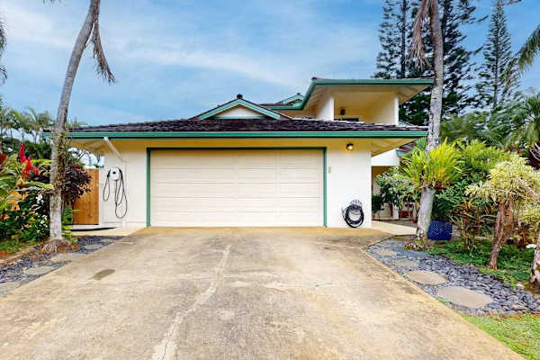 Kohola Hale exterior shows garage entry palms and welcoming driveway