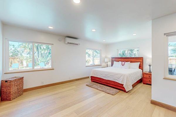 First Bedroom features crisp linens warm wood floors and garden light