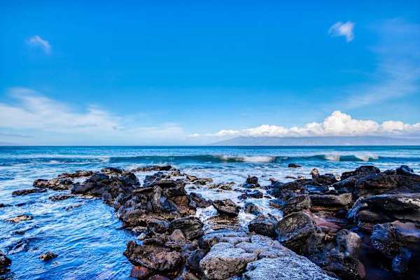 Turquoise waves crash along the rocky shoreline.