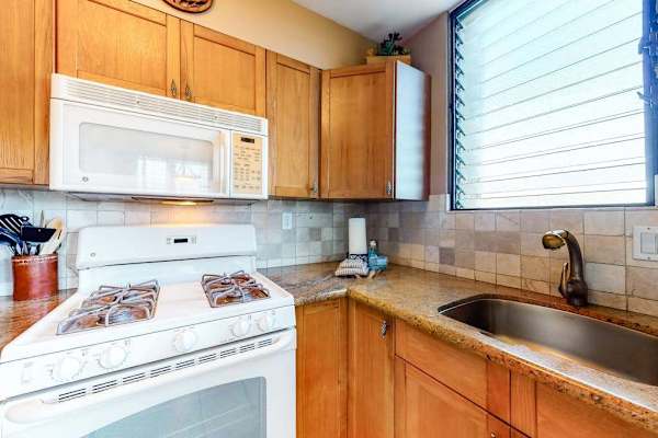 Fully Equipped Kitchen with Gas Stove, Overhead Microwave, and Tile Backsplash