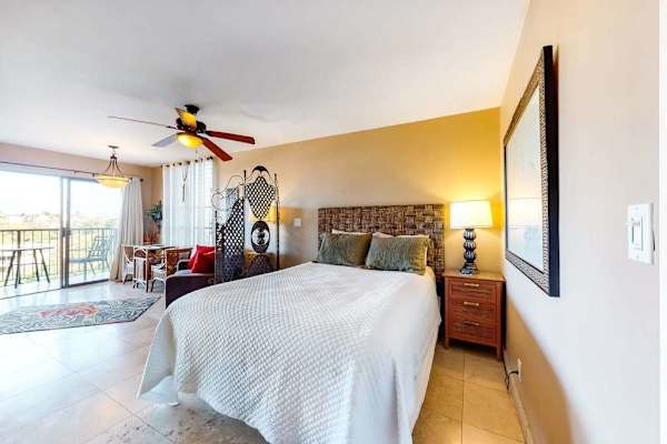 Spacious Studio Bedroom with Bedside Lamp and View toward Balcony