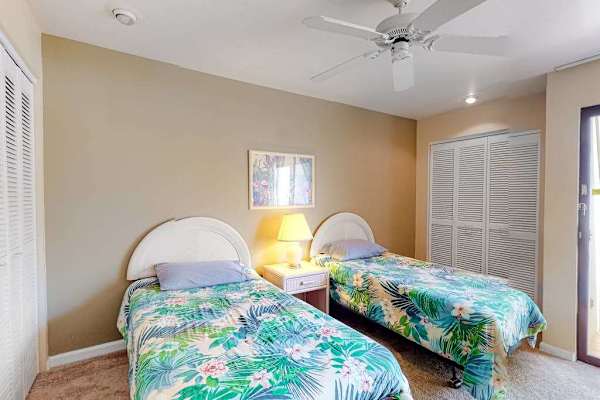 This bedroom features twin beds ceiling fan and natural light