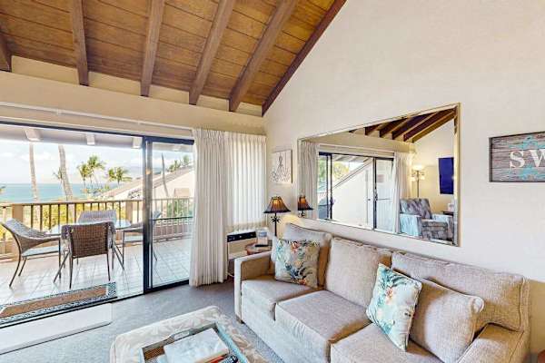 Open-Concept Living Room with Vaulted Ceilings, Comfortable Sofa, and Balcony Access
