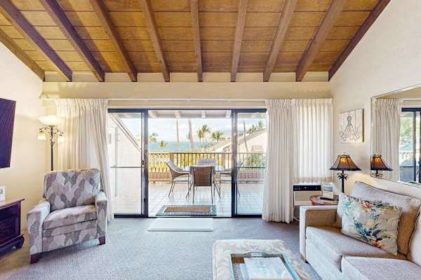 Sunlit Living Room with Vaulted Ceilings, Armchair, and Ocean-View Balcony Access