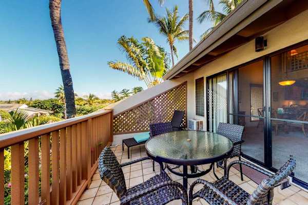 Balcony dining set overlooks palm trees and Maui resort landscaping