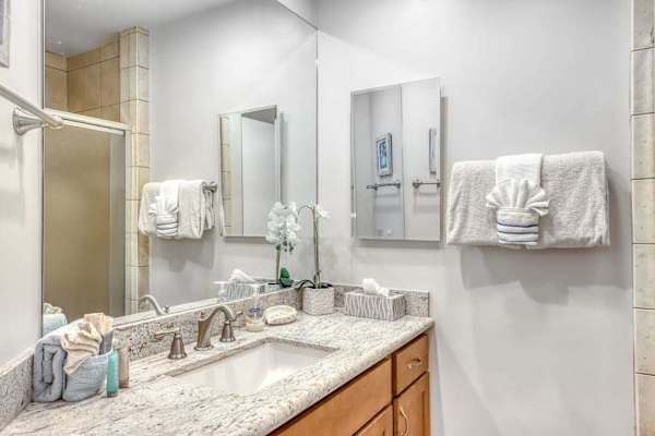Full Bathroom vanity features wood cabinetry wide counters and mirrors
