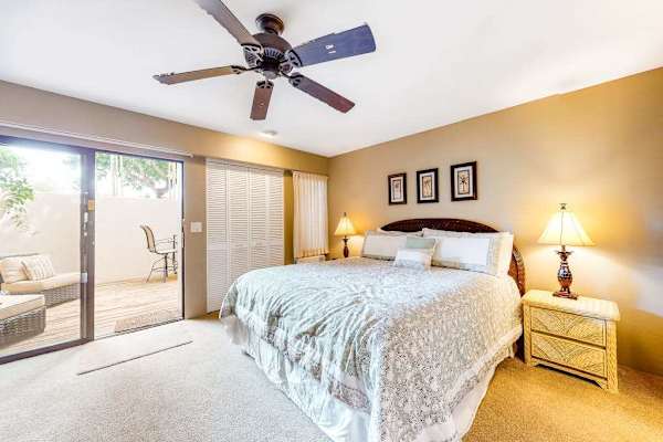 Bedroom features restful bedding and convenient tropical garden views