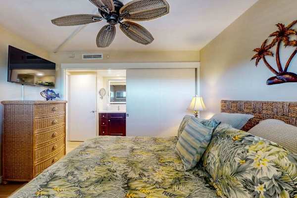 Primary bedroom with king bed, ceiling fan, en suite bathroom and a flat screen TV