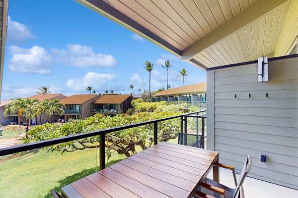 Covered balcony overlooks green lawns, palm trees, and distant ocean