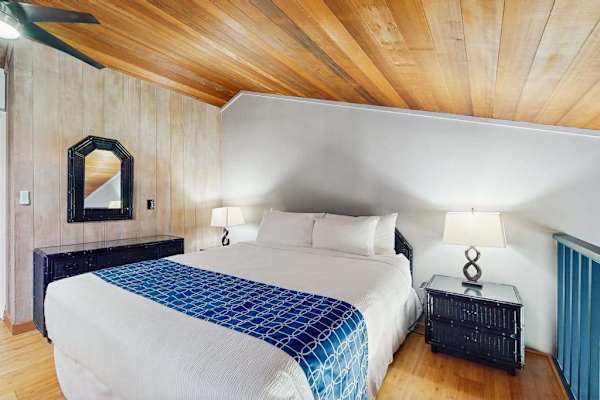 Cozy bedroom features comfortable bedding, wood ceilings, and bedside lamps