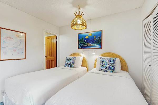 The bright guest bedroom features two comfortable beds for a restful island stay.