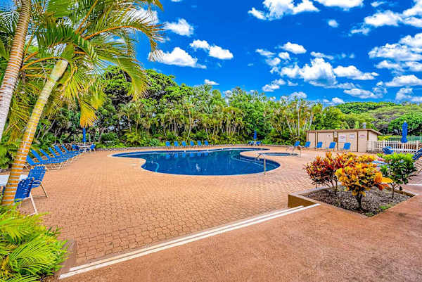 Resort pool offers sunny seating amid tropical palms and gardens