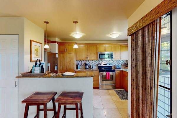 Fully Equipped Kitchen with Stainless Steel Appliances, Breakfast Bar, and Wooden Stools