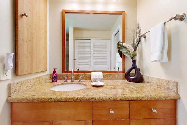 Clean Bathroom Vanity with Large Mirror, Granite Countertop, and Natural Wood Storage