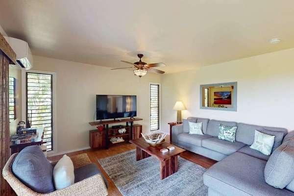 Sunlit Living Room with L-Shaped Sectional Sofa, Smart TV, and Air Conditioning