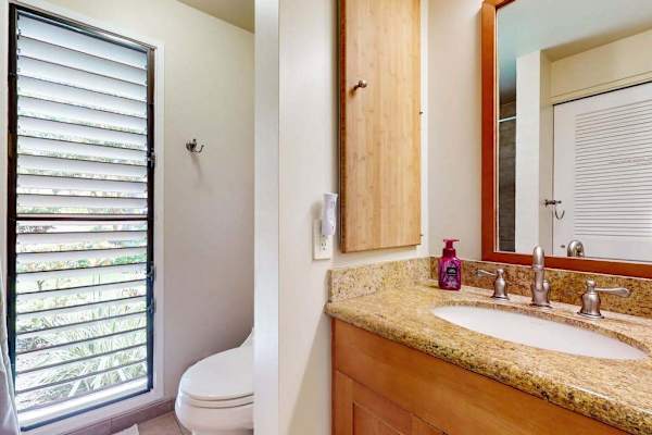 Bathroom Vanity Area with Granite Countertop, Wooden Cabinetry, and Louvered Window