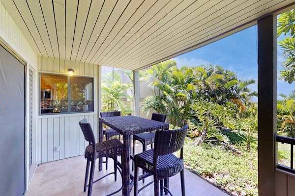Covered Patio Dining Area with High-Top Wicker Seating and Tropical Views