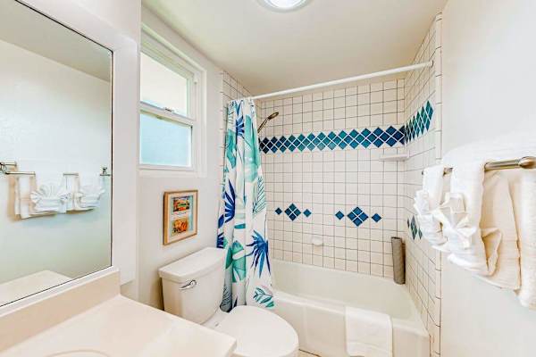 This bright, coastal-themed bathroom features a patterned blue and white tile accent wall above a white bathtub.