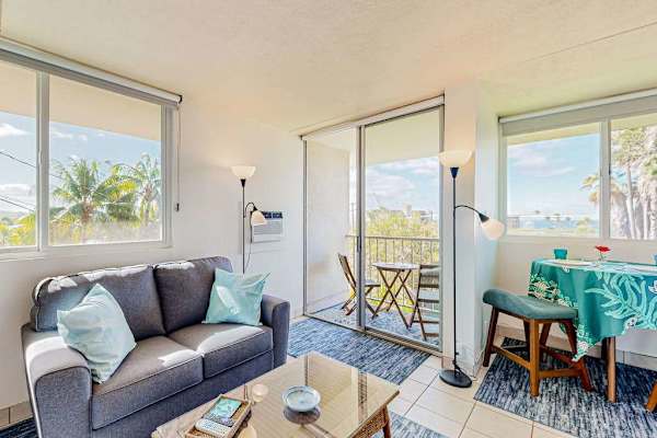 Brightly lit condo interior featuring a dining area and a sofa set next to a sliding door that opens onto a balcony.