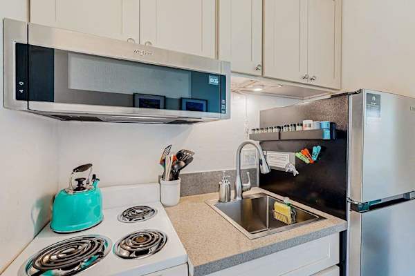 Kitchen area with a Whirlpool over-the-range microwave and a light blue kettle 