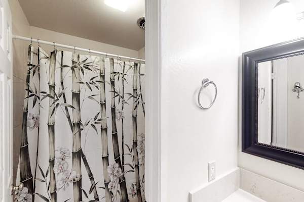 Full bathroom features patterned shower curtain bright vanity and mirror