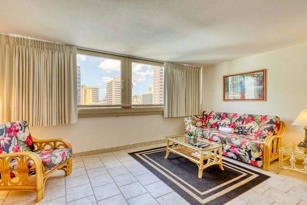 Bright and spacious living room with large windows showcasing beautiful Waikiki city views and plenty of natural light.