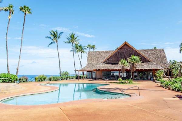 Resort pool and pavilion overlook palm trees and Pacific Ocean