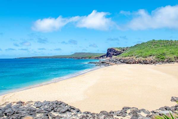 Sandy beach curves along brilliant turquoise water beneath blue skies