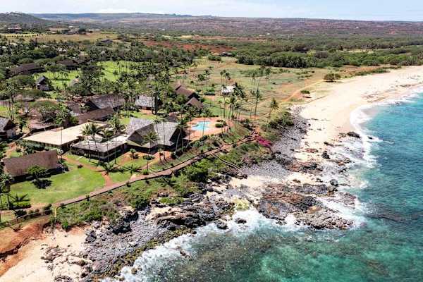 Aerial panorama highlights resort pool palms and sweeping coastal scenery