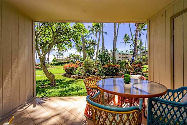 Covered patio dining space overlooks lush gardens and tropical landscaping