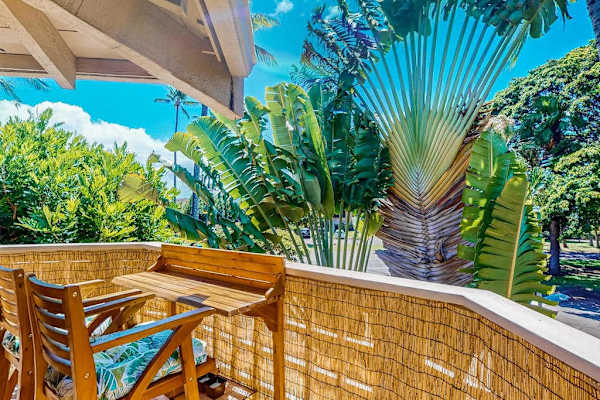 Balcony dining table sits beside tropical foliage and open-air views