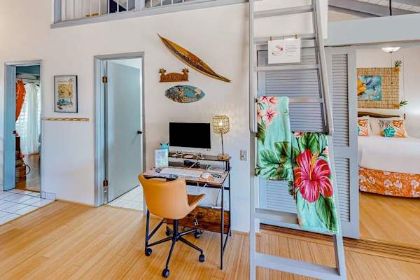 Living room workspace includes desk, chair, television, plants, and shelving