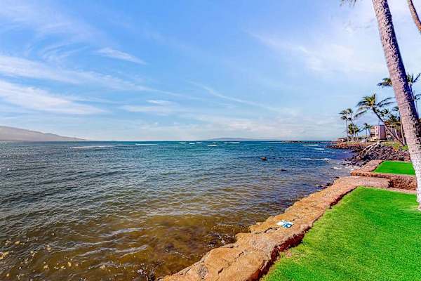 Oceanfront manicured lawns, swaying palm trees, and turquoise Pacific waters create a picture-perfect setting as waves gently crash along the shoreline.