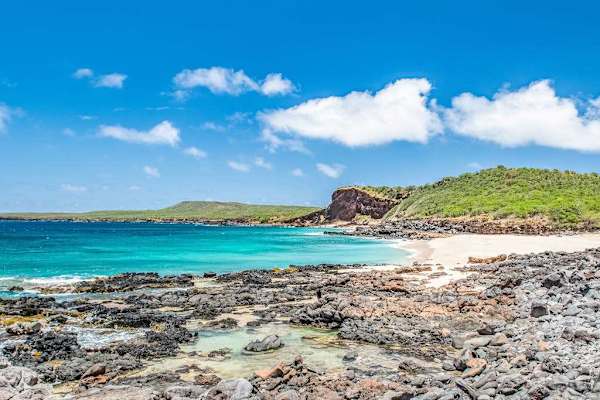 Rocky shoreline displays clear blue water and peaceful island scenery
